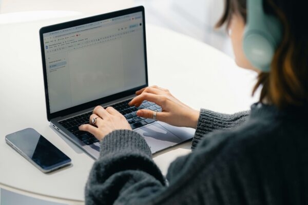 Woman on laptop with phone in view